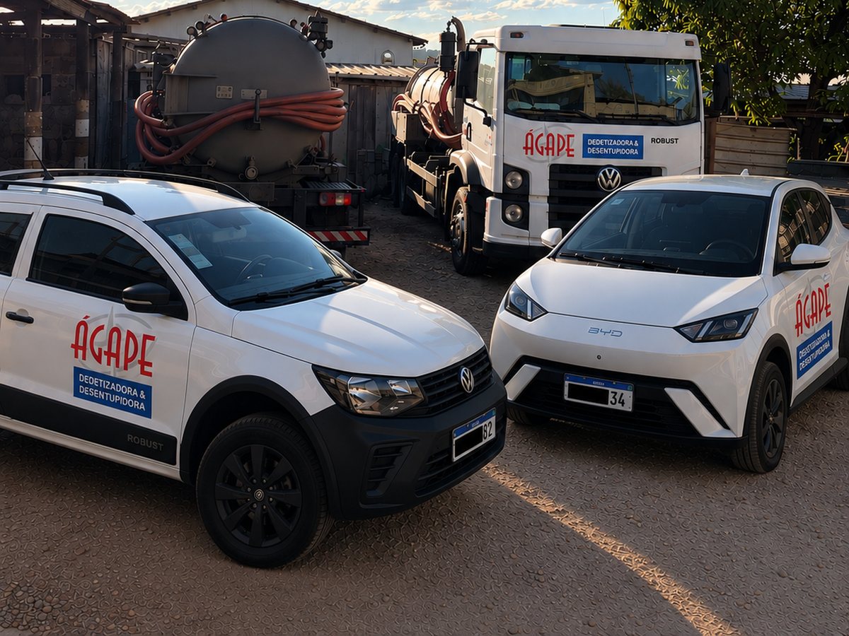 Caminhões com tanque e mangueiras e dois carros brancos com a marca Ágape Dedetizadora & Desentupidora, estacionados ao ar livre